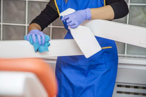 Cleaner dusting and maintaining a modern kitchen during a recurring visit in Westhampstead